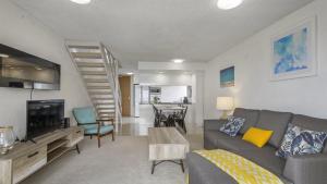 a living room with a gray couch and a staircase at Beachpark Apartments - Close To Beach in Port Macquarie