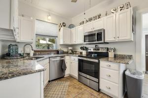 a kitchen with white cabinets and granite counter tops at Pelican Place - Waterfront launch and fire pit in Cedar Key