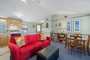 Una sala de estar con un sofá rojo y una cocina. en Rains Waterfront Cottage, en Cedar Key