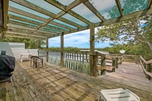 una terraza de madera con pérgola, mesa y sillas en Rains Waterfront Cottage, en Cedar Key