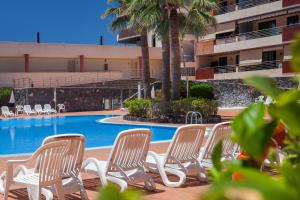 un groupe de chaises assises à côté d'une piscine dans l'établissement Tenerife Break - Balcon de los Gigantes, à Puerto de Santiago