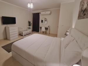 biała sypialnia z dużym łóżkiem i telewizorem w obiekcie El Rehab, 3 BR Apt Garden view Sweet Homies w mieście New cairo