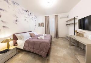 een slaapkamer met een bed, een bureau en een tv bij Loggia Senensis in Siena