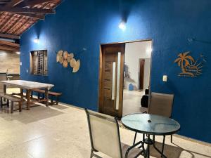 a dining room with a table and a blue wall at Casa Praiana pé na areia Morro Branco in Beberibe
