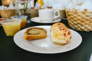 a white plate with a sandwich and bread on a table at Pousada SerTão de Minas in Conceição da Ibitipoca