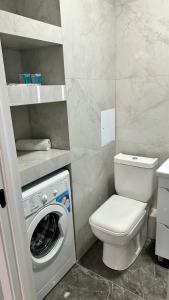 Un baño con inodoro y lavadora. en Новая студия в самом центре города, en Almaty