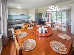 a kitchen and dining room with a wooden table and chairs at Stonewall in Jindabyne