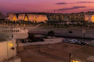 Kush Hotel, Grand Museum & Pyramids View في القاهرة: مدينة في الليل مع سيارات تقف في موقف للسيارات