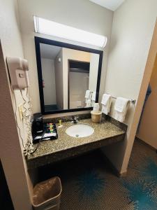a bathroom with a sink and a large mirror at Days Inn & Suites by Wyndham Brinkley in Brinkley +4 photos