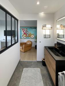 ein Badezimmer mit einem Waschbecken und ein Wohnzimmer in der Unterkunft L'escapage Vintage - Gîte - 2 chambres in Eschau