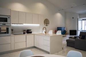 eine Küche mit weißen Schränken und ein Wohnzimmer in der Unterkunft Casa Terra Mar in Angra do Heroísmo