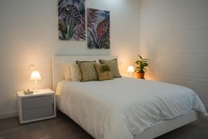 ein Schlafzimmer mit einem weißen Bett mit zwei Gemälden an der Wand in der Unterkunft Casa Terra Mar in Angra do Heroísmo