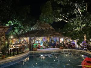 a swimming pool at night with a bar and tables at Big Apple Dive Resort in Puerto Galera