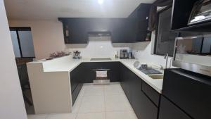 a small kitchen with black and white cabinets and a sink at Everest 663 in Monterrey