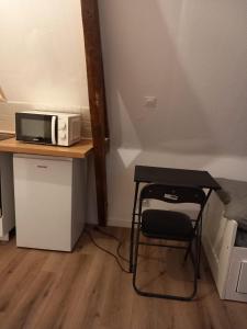 einen kleinen Tisch mit einer Mikrowelle und einem Stuhl in der Unterkunft Hébergement Cozy à Deville-lès-Rouen - 13 min Rouen in Déville-lès-Rouen