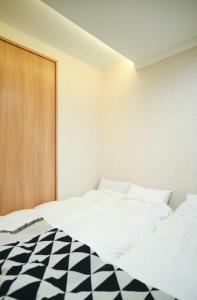 a bedroom with a bed with black and white sheets at 天下茶屋駅1分シャワートイレ各階付き関西空港直通wifiあり in Osaka