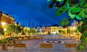 a city square at night with benches and buildings at Apartament Puck Przestronny i Nowoczesny in Puck