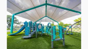 a playground in a park with blue equipment at Margate Retreat Pool Near Beach Bbq in Margate