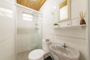a white bathroom with a toilet and a sink at Casa 2 quartos, 6 pessoas, perto da praia, ar condicionado, wi-fi, cozinha completa, lavanderia, in Florianópolis