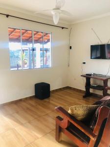 a living room with a couch and a tv and a table at Chácara Espelho D água in Vargem