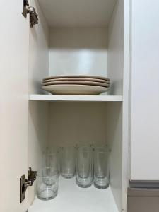um prato e copos numa prateleira num armário em Aconchegante apt em Joao Pessoa em João Pessoa mais 26 fotografias