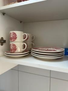 dois pratos e duas chávenas e pires numa prateleira em Aconchegante apt em Joao Pessoa em João Pessoa