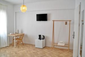 a room with a table and a television on a wall at Tzatziki Boutique Rooms in Kavala