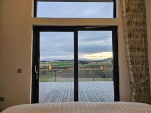 a bedroom with a large glass door with a view at Woodland Lodge in Huntly