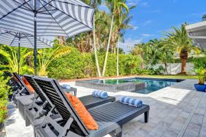 ein Paar Stühle und ein Sonnenschirm neben einem Swimmingpool in der Unterkunft Coconut Clubhouse - Heated Pool - Hot tub - Ping Pong in Fort Lauderdale