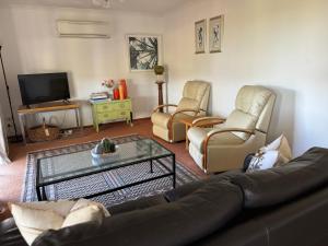 a living room with a couch and chairs and a tv at Bonnie Views Cottage in Clunes