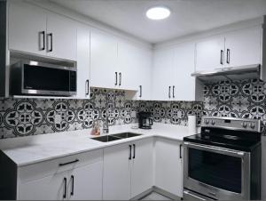 a kitchen with white cabinets and a black microwave at A new luxury basement apartment in Surrey