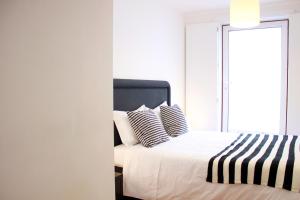 Schlafzimmer mit einem Bett mit schwarzen und weißen Kissen in der Unterkunft JOIVY Modern 1-bed Apt with terrace, moments from São Bento Palace in Lissabon