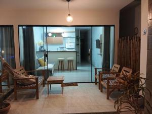 a living room with glass doors and chairs and a kitchen at Casa beach Japaratinga in Japaratinga