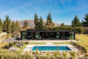 a modern house with a swimming pool and a house at Riverbank by Sothebys Luxury Rental Homes in Wanaka