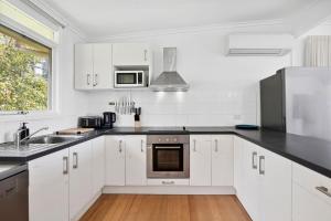 a kitchen with white cabinets and a stainless steel appliance at Prasino in Lorne +9 photos
