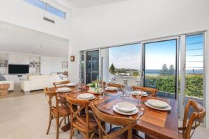 a dining room with a table and chairs and a large window at Riverleigh, Gerroa in Gerroa