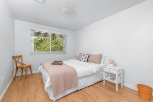 a white bedroom with a bed and a chair at Riverleigh, Gerroa in Gerroa