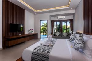 a bedroom with a large white bed and a television at Pondok Deamore Villa in Gianyar