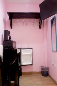 a room with a pink wall with a counter and a mirror at Imani's Inn in Placencia Village +29 photos