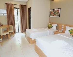 une chambre d'hôtel avec deux lits et un bureau dans l'établissement Pearl Vista de Coron Resort Hotel, à Coron