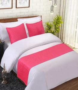 a bed with pink and white sheets and pillows at Hotel Oasisinn in Hyderabad
