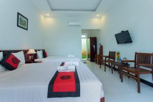 a bedroom with two beds and a flat screen tv at La Uy Villa in Hoi An +22 photos