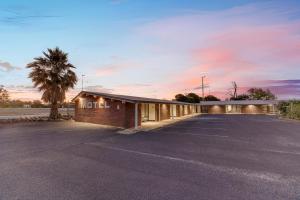 a building with a palm tree in front of a parking lot at Parkview Motor Inn in Parkes +105 photos