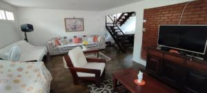 un salon avec une télévision à écran plat et des chaises dans l'établissement Casa em Cabo Frio, BAIRRO PALMEIRAS, à Cabo Frio