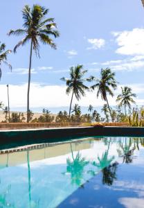 ein Swimmingpool mit Palmen im Hintergrund in der Unterkunft Vista Milagres in São Miguel dos Milagres