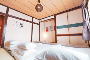 two beds in a room with wooden ceilings at South Furano House in Furano