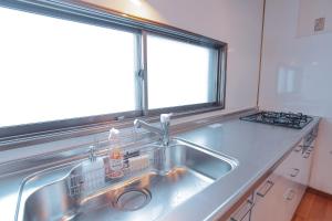 a kitchen sink with a dish drying rack next to a window at South Furano House in Furano +27 photos