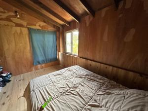 Ce lit se trouve dans une chambre en bois dotée d'une fenêtre. dans l'établissement Cabaña lo de Antonia, à Estación Costa Azul 1 autre photo