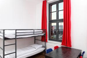 a room with bunk beds and a table and a window at Hostel am GÜTERBAHNHOF in Neubrandenburg