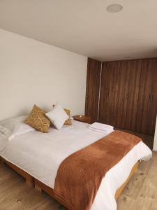 a bedroom with a large bed with white sheets and pillows at Apartamento Nuevo, Tulipán Amarillo in Sogamoso